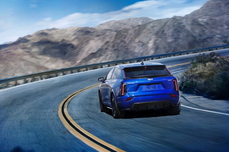 Rear View of a Blue 2026 OPTIQ-V Driving on a Curve of a Mountain Row | Wheeler Chevrolet Cadillac in Yuba City CA