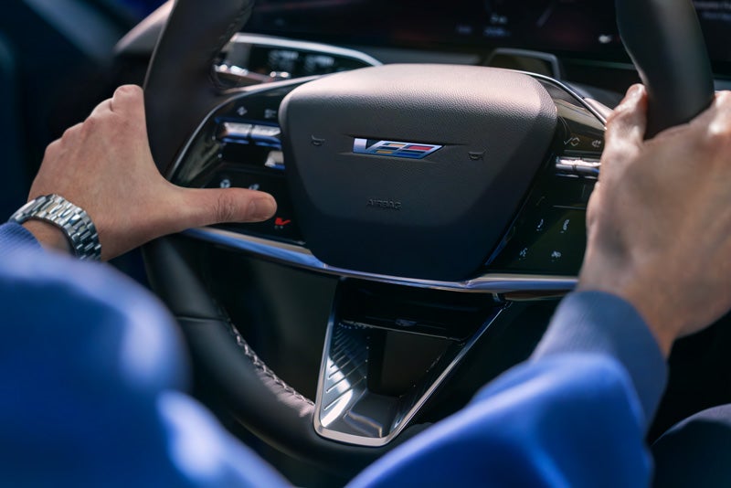 Close-up of a Man About to Press the V-Button on the 2026 OPTIQ-V Steering Wheel | Wheeler Chevrolet Cadillac in Yuba City CA